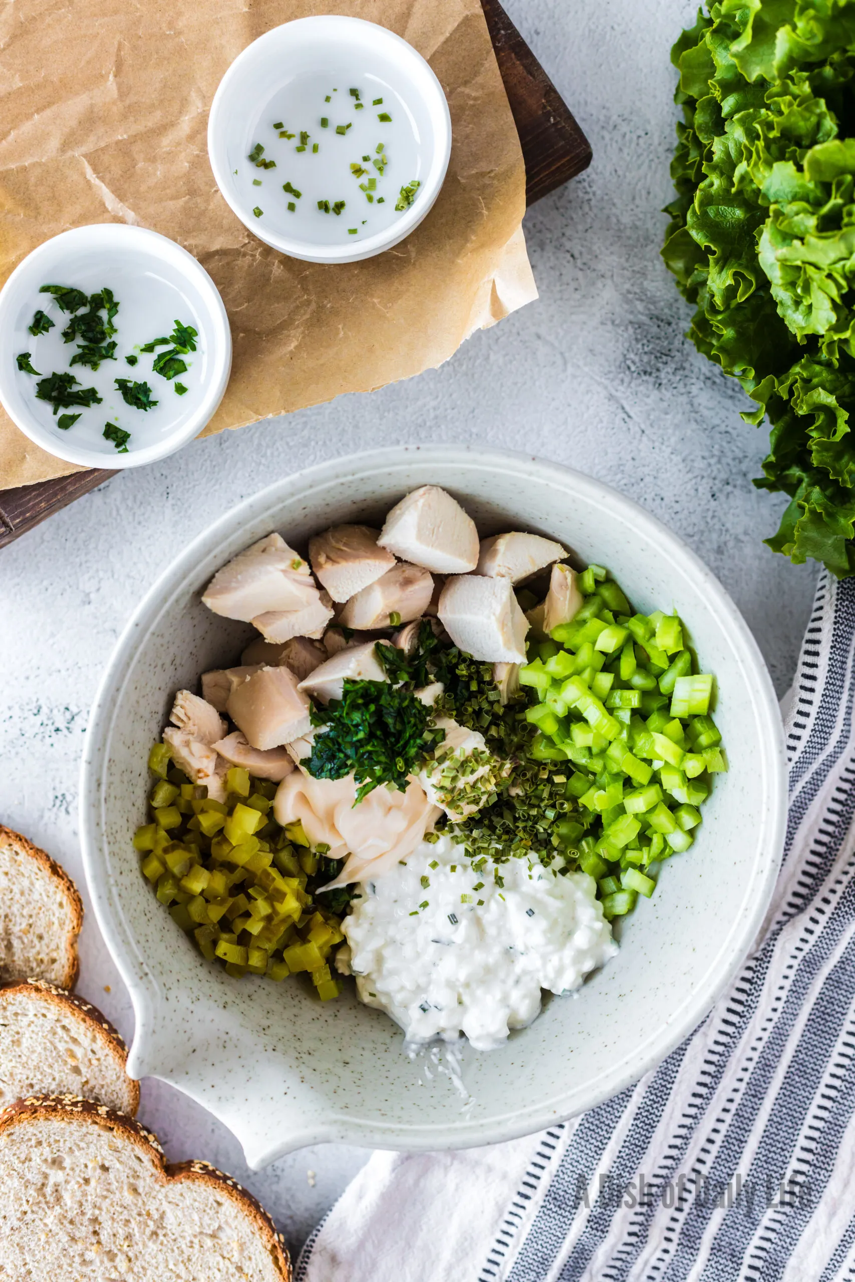 chopped chicken, pickle, celery, cottage cheese, parsley, chives, mayonnaise, salt and pepper added to a bowl unmixed