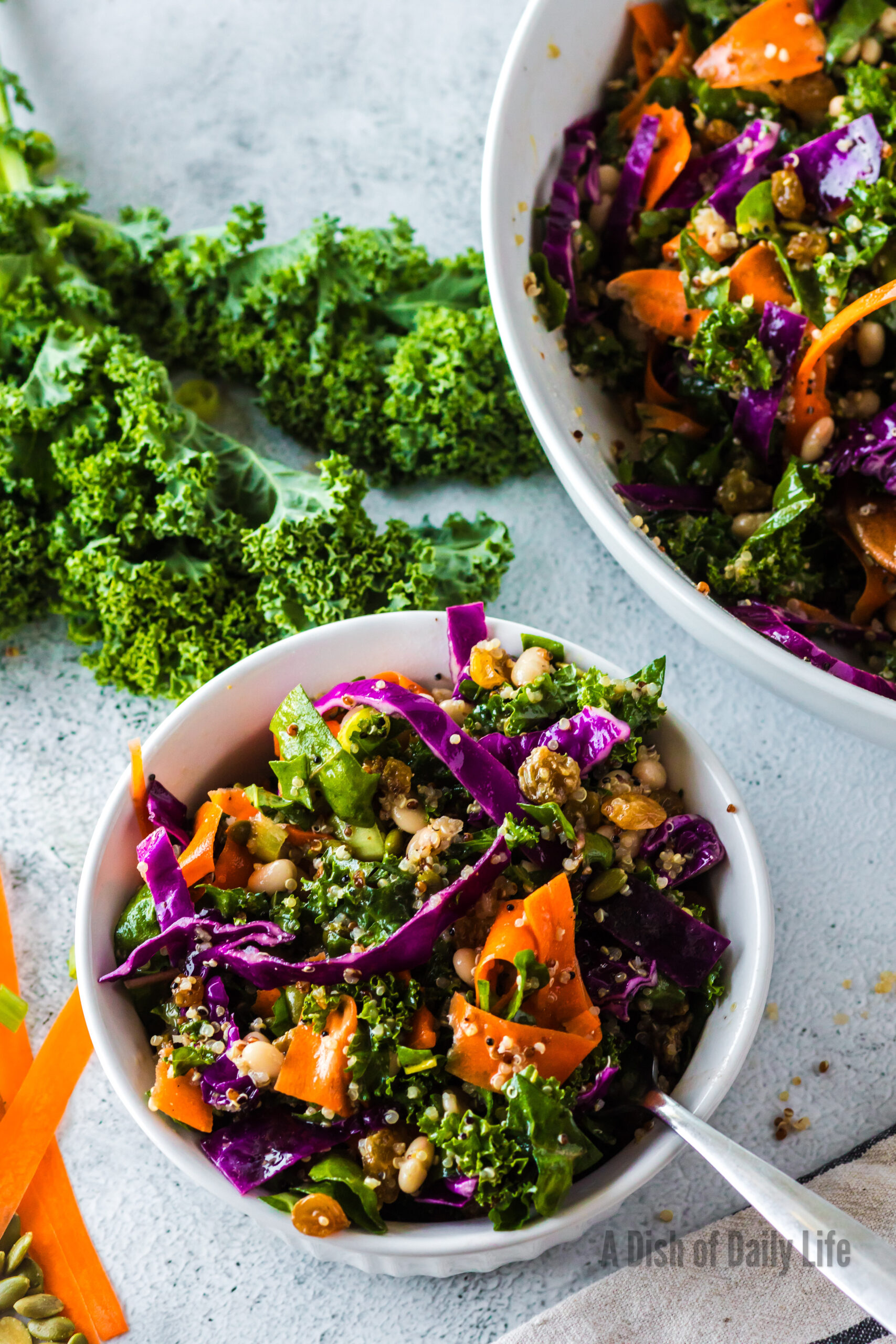 zoomed out image of serving bowl full of salad and a individual portion bowl of salad