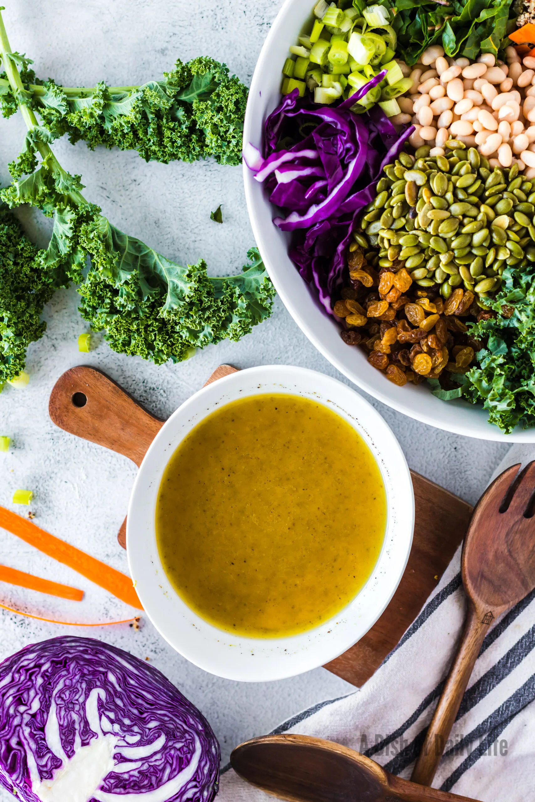 Lemon dressing in a bowl next to prepared salad