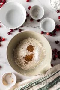flour, baking powder, cinnamon, and nutmeg added to a bowl.