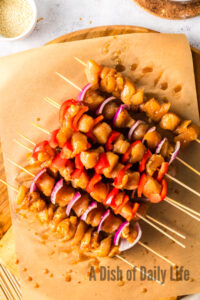 Chicken with onion and bell pepper layered on wooden skewers, ready to grill.