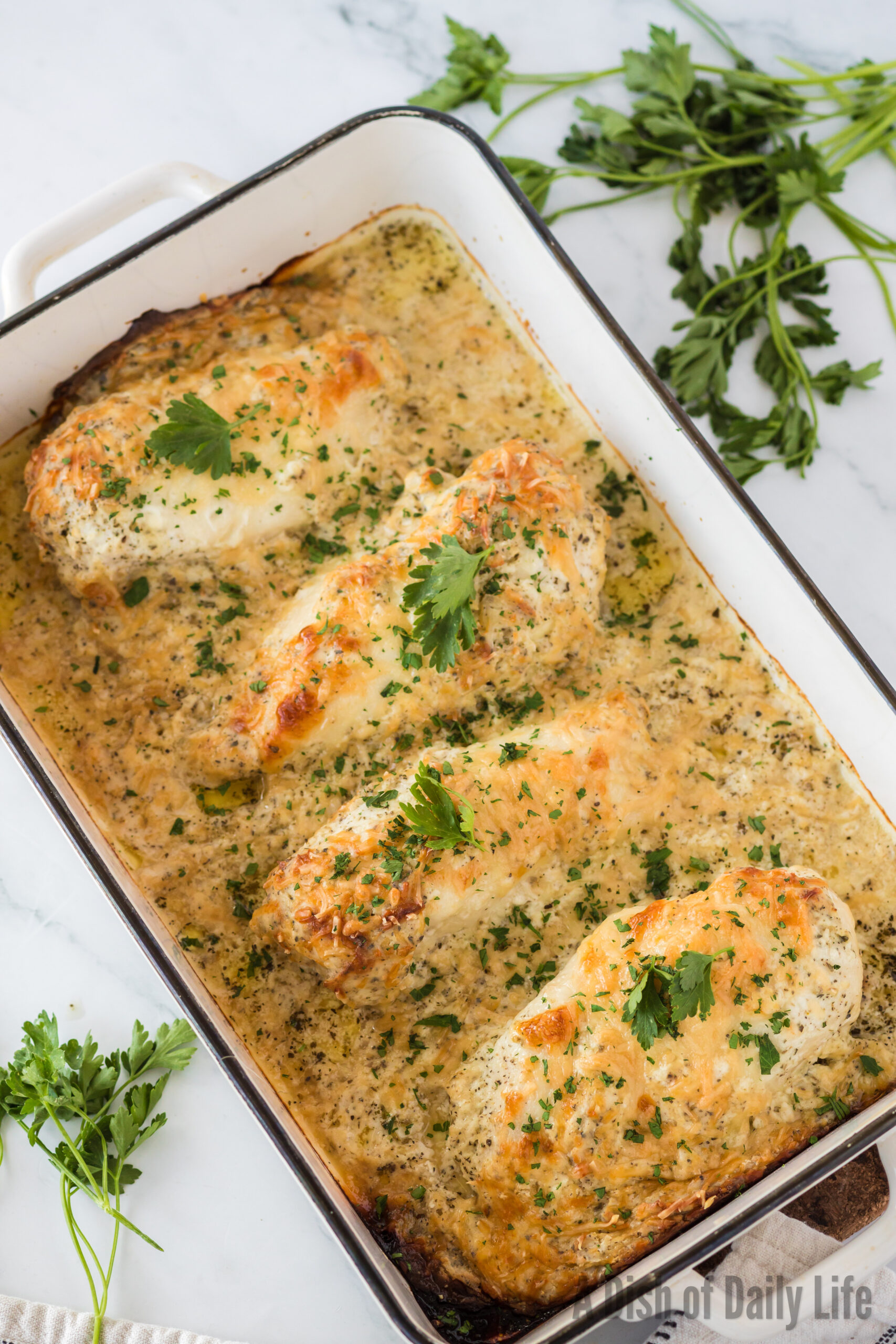 top view looking down at baked chicken in casserole dish. Dish tilted to the left