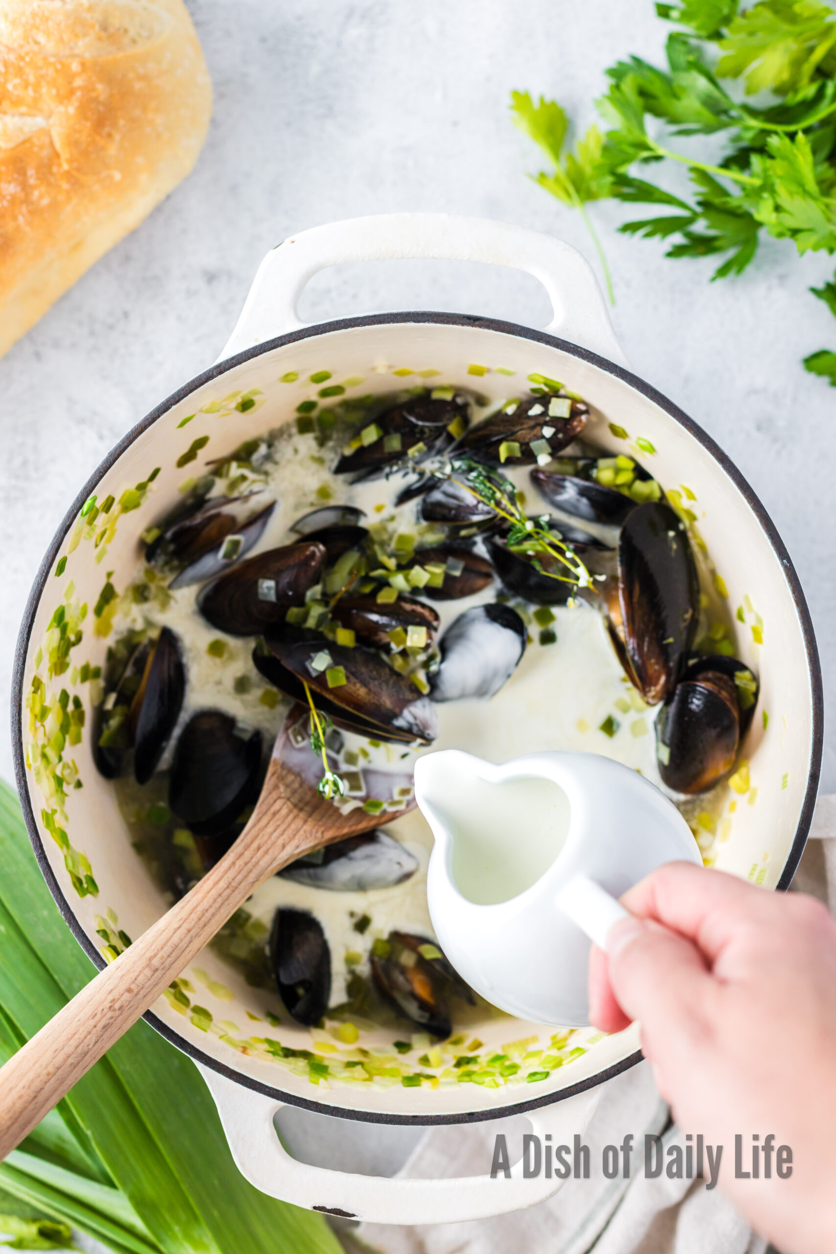 tempered cream sauce being added to mussels.