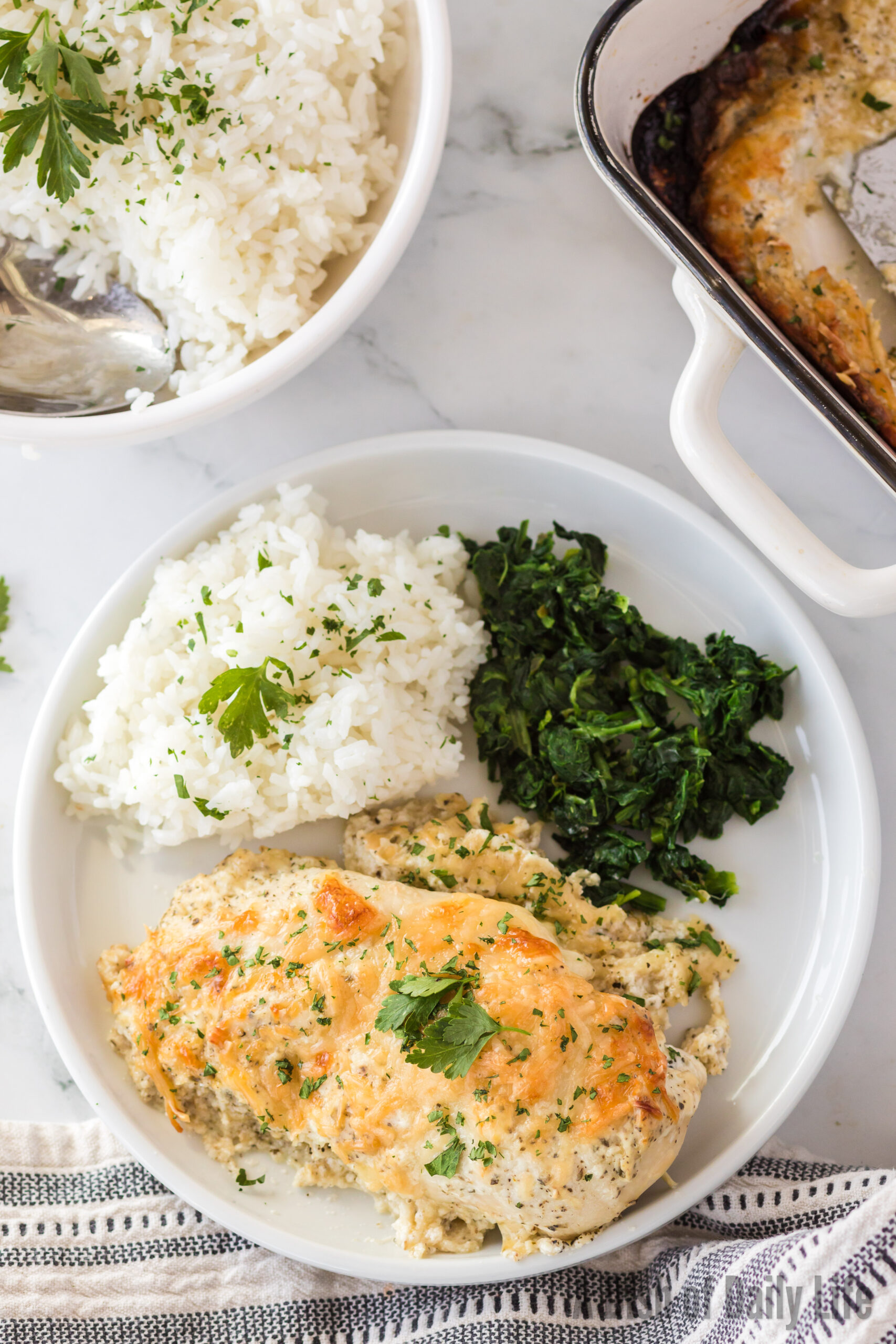 top view looking down at chicken on a plate with rice and cooked spinach