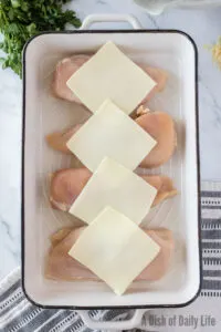 4 chicken breasts laid out in casserole and topped with a slice of mozzarella