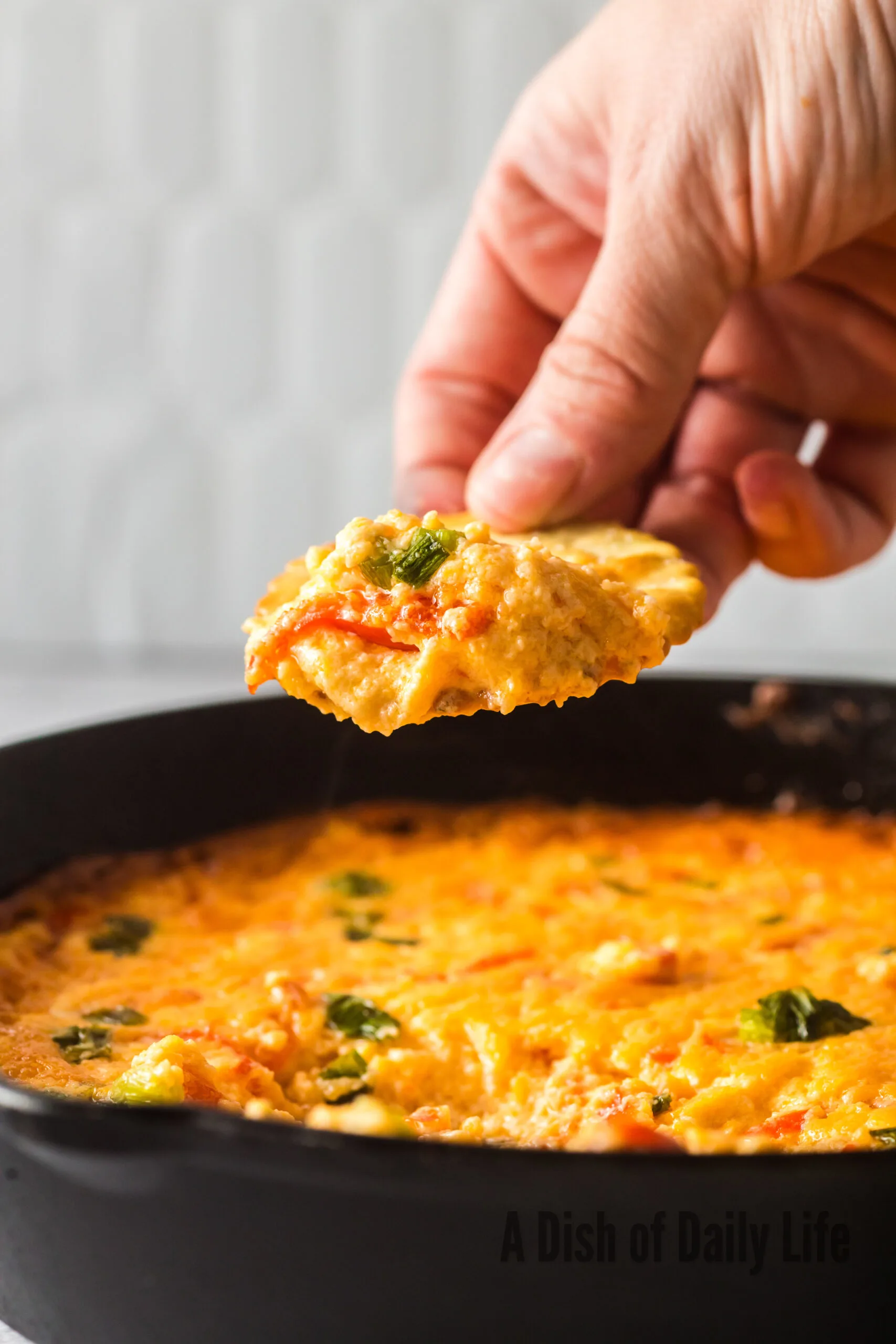 Hand scooping a portion of dip out of skillet