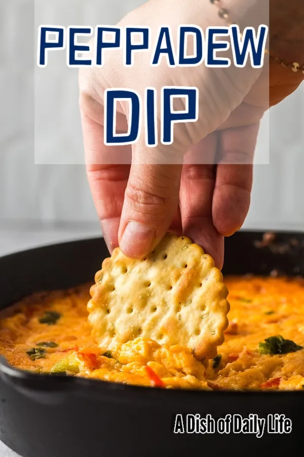 Main image of peppadew cheese dip. Hand scooping hot dip out of skillet.