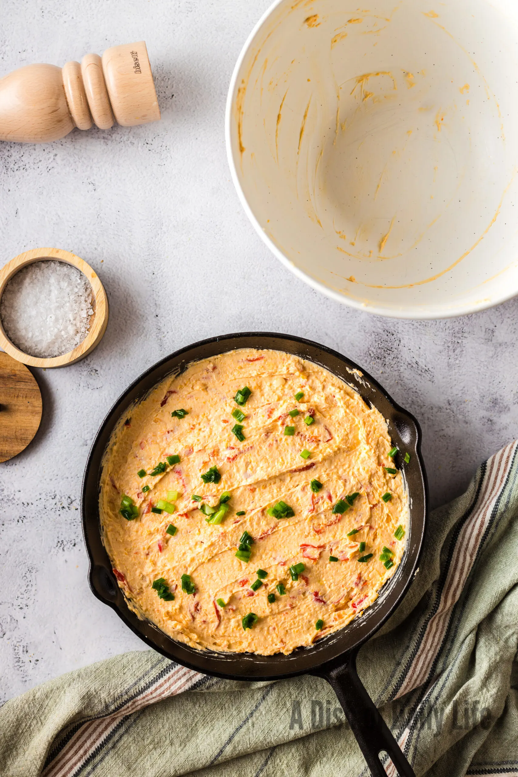 green onions sprinkled on top of unbaked peppadew cheese dip in skillet