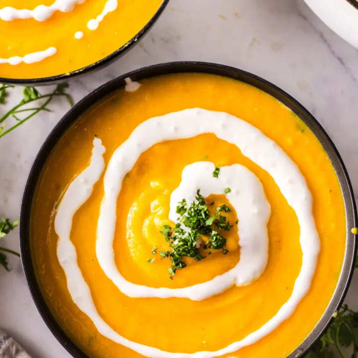 3 bowls of soup laid out on counter topped with additional creme fraiche and cilantro.