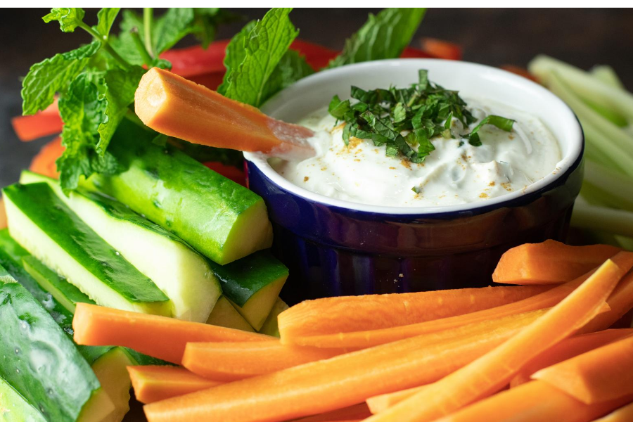 Carrot being dipped into Greek Yogurt Tahini Sauce