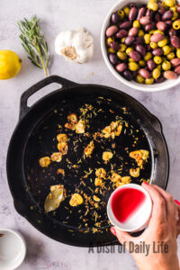 red wine vinegar added to garlic in skillet.