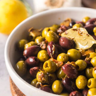 zoomed in image of olives in a serving bowl with garlic and vinegar on top