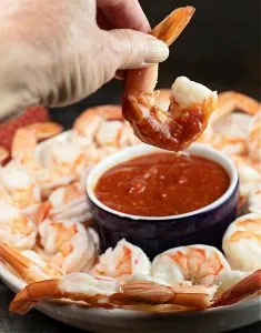 Shrimp being dipped in homemade cocktail sauce