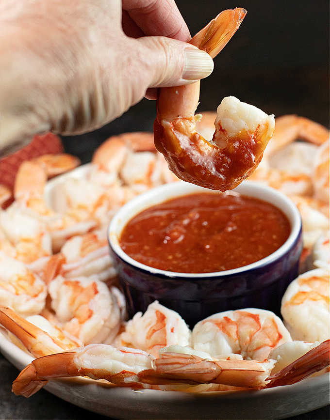 Shrimp being dipped in homemade cocktail sauce