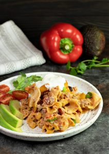 Mexican Taco Noodle Casserole on a plate with sliced cherry tomatoes and avocado for garnish