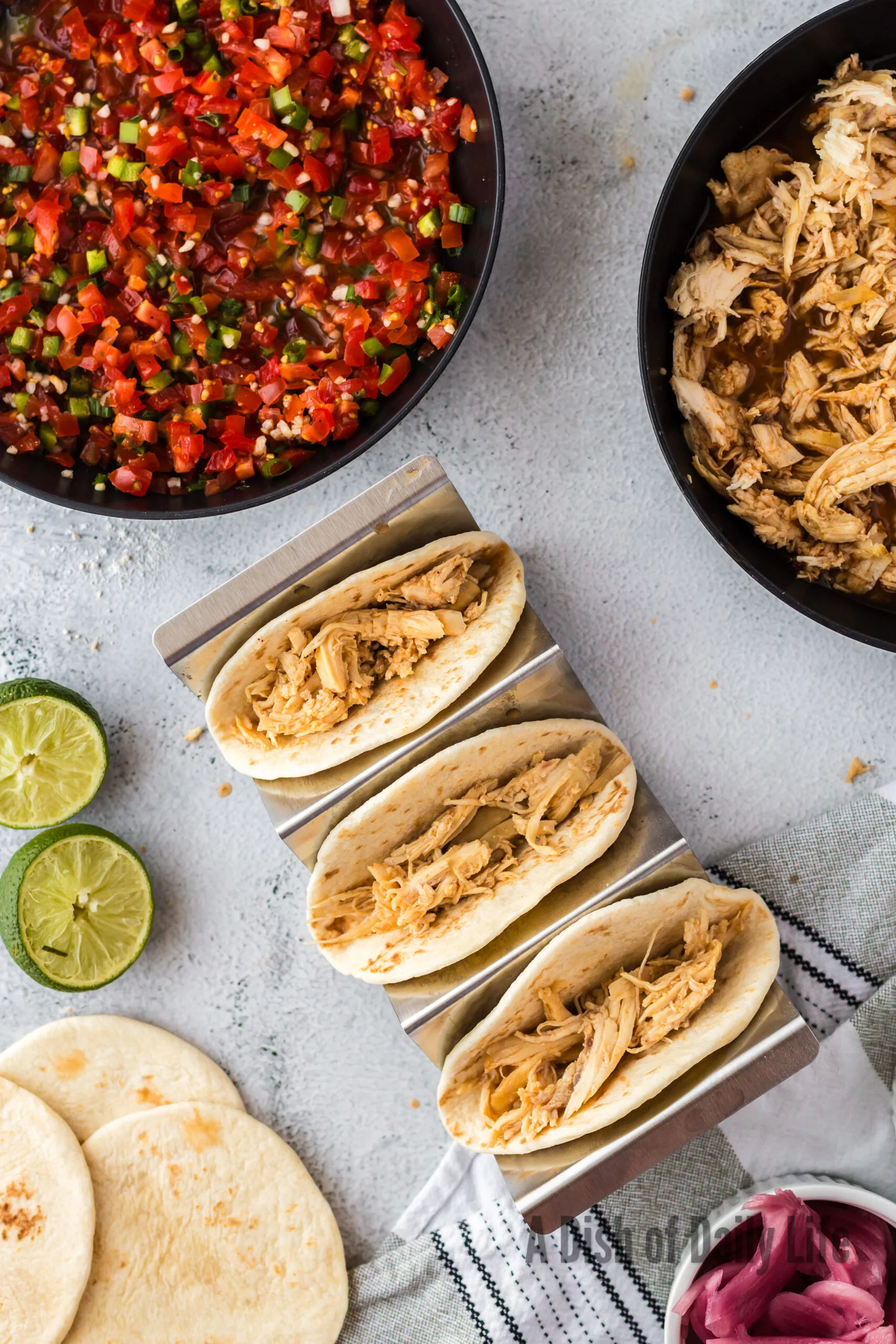 3 tortillas in a taco stand filled with shredded chicken