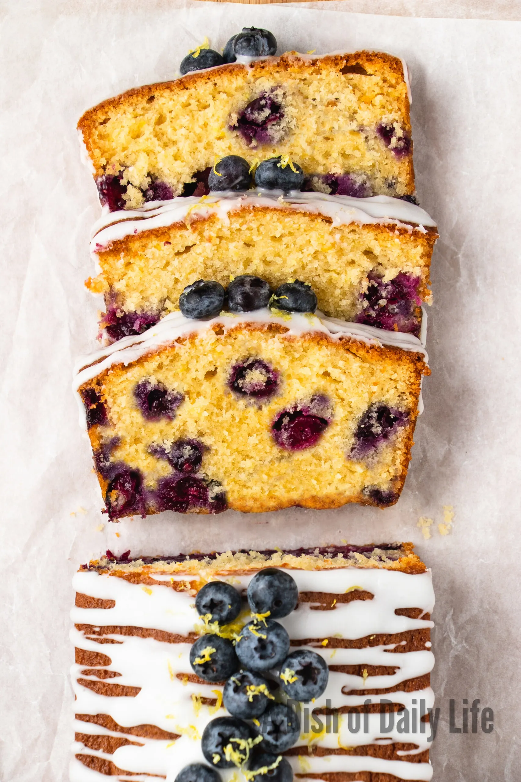 zoomed in image of loaf cake laid out on parchment paper with three slices cut facing the top half of the image