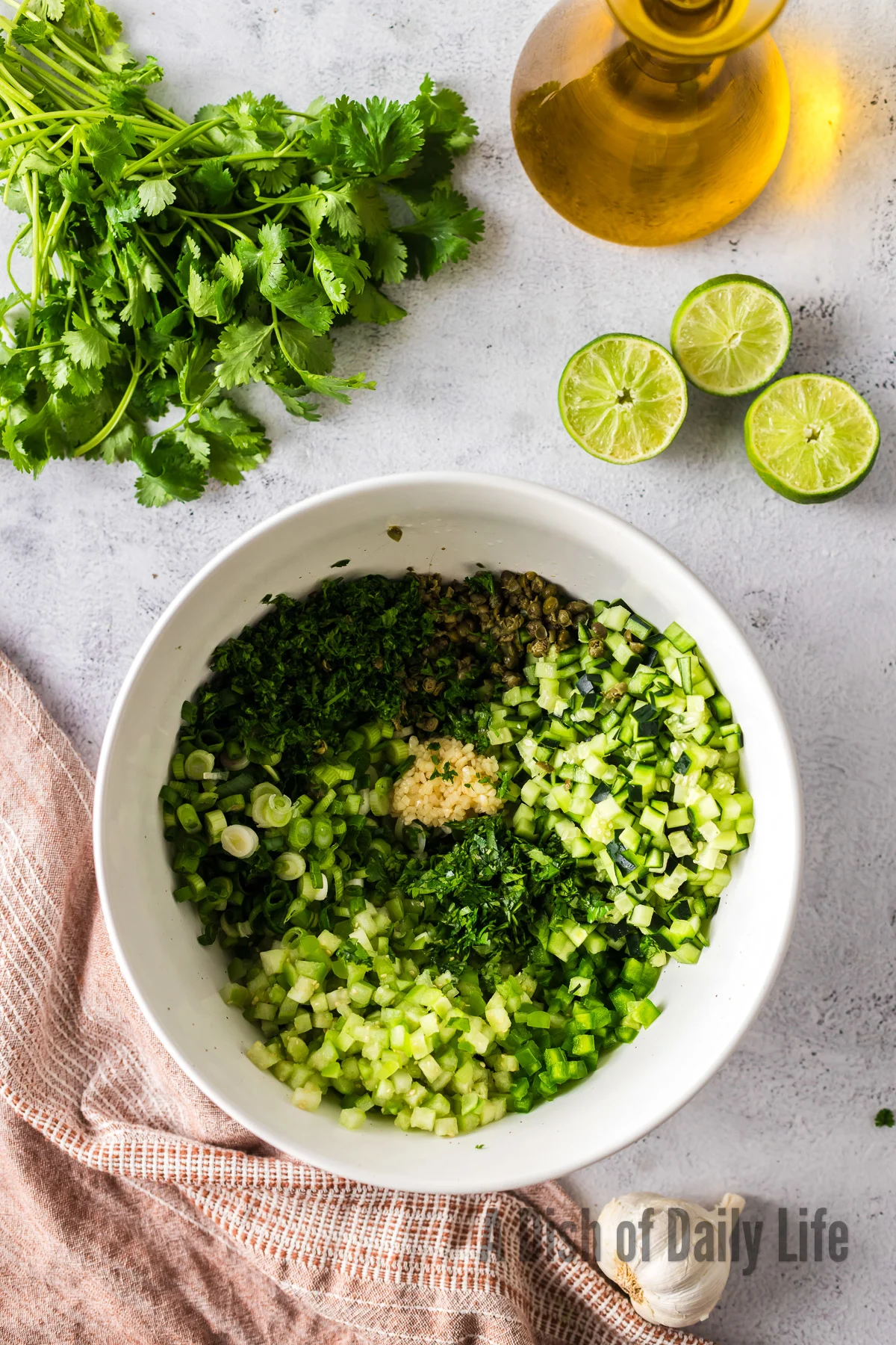 diced tomatillos, scallions, jalapeno, cucumber, limes, capers, garlic, parsley and cilantro in a bowl