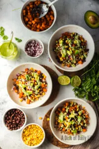 Avocado and Dressing added on top of red onions, corn, black beans, sweet potatoes and farro