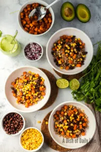 Corn added to the top of black beans, sweet potatoes and farro