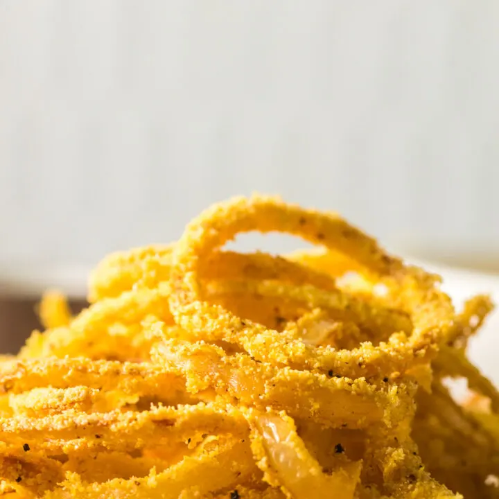 crispy fried onions stacked high on a paper plate