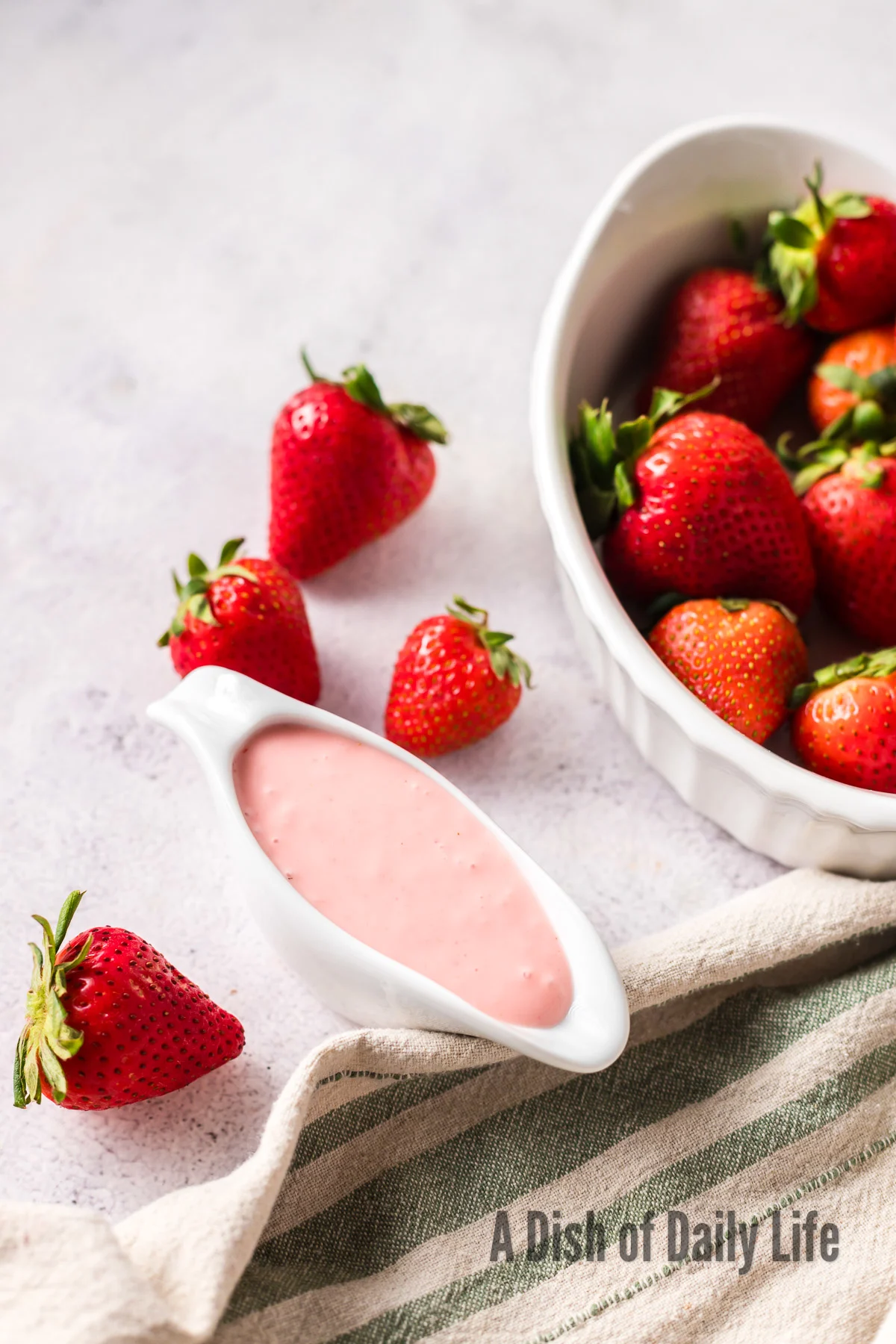salad dressing in gravy boat next to a bowl of strawberries