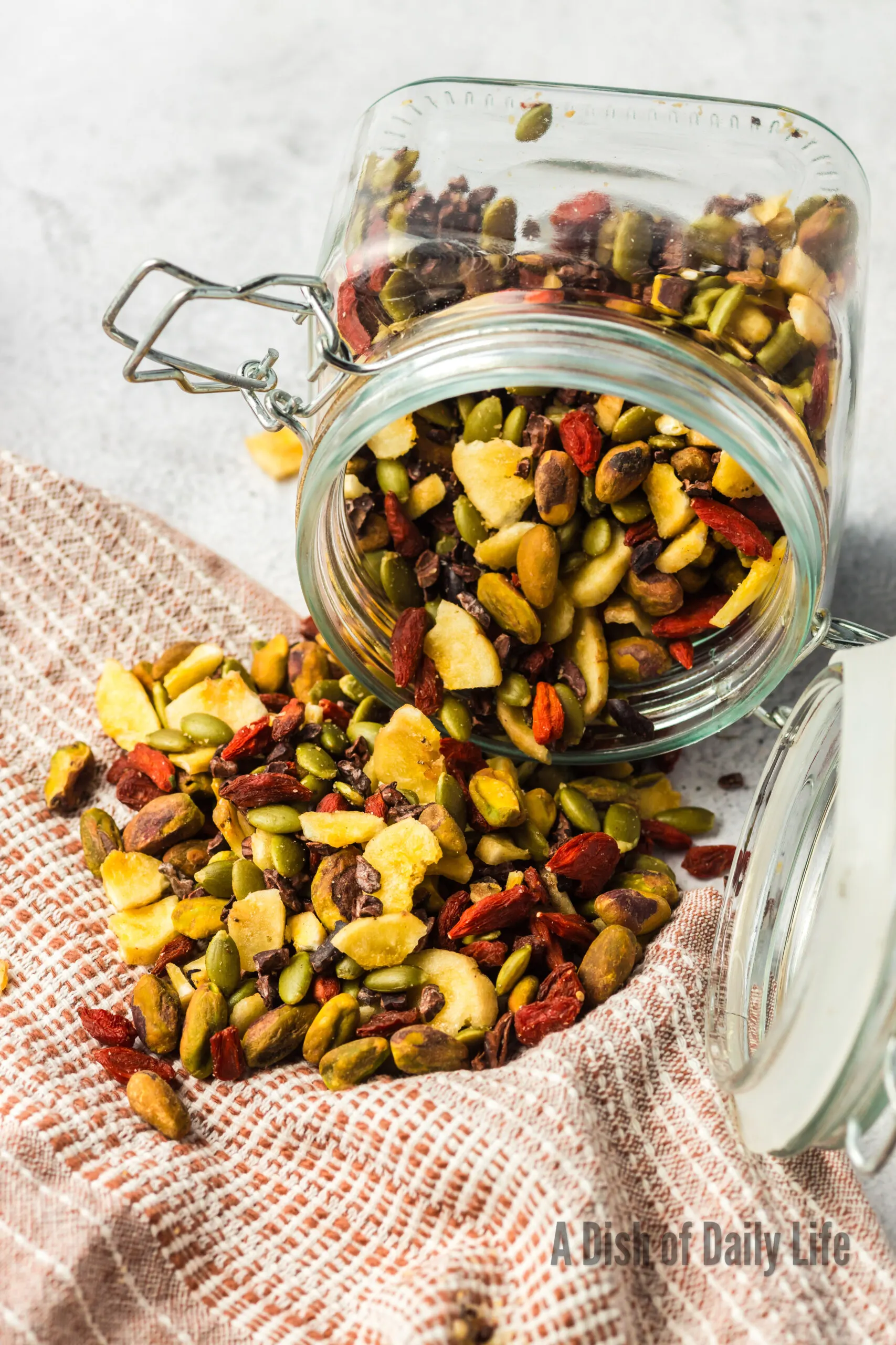 jar of healthy snack mix spilling onto a towel on counter.