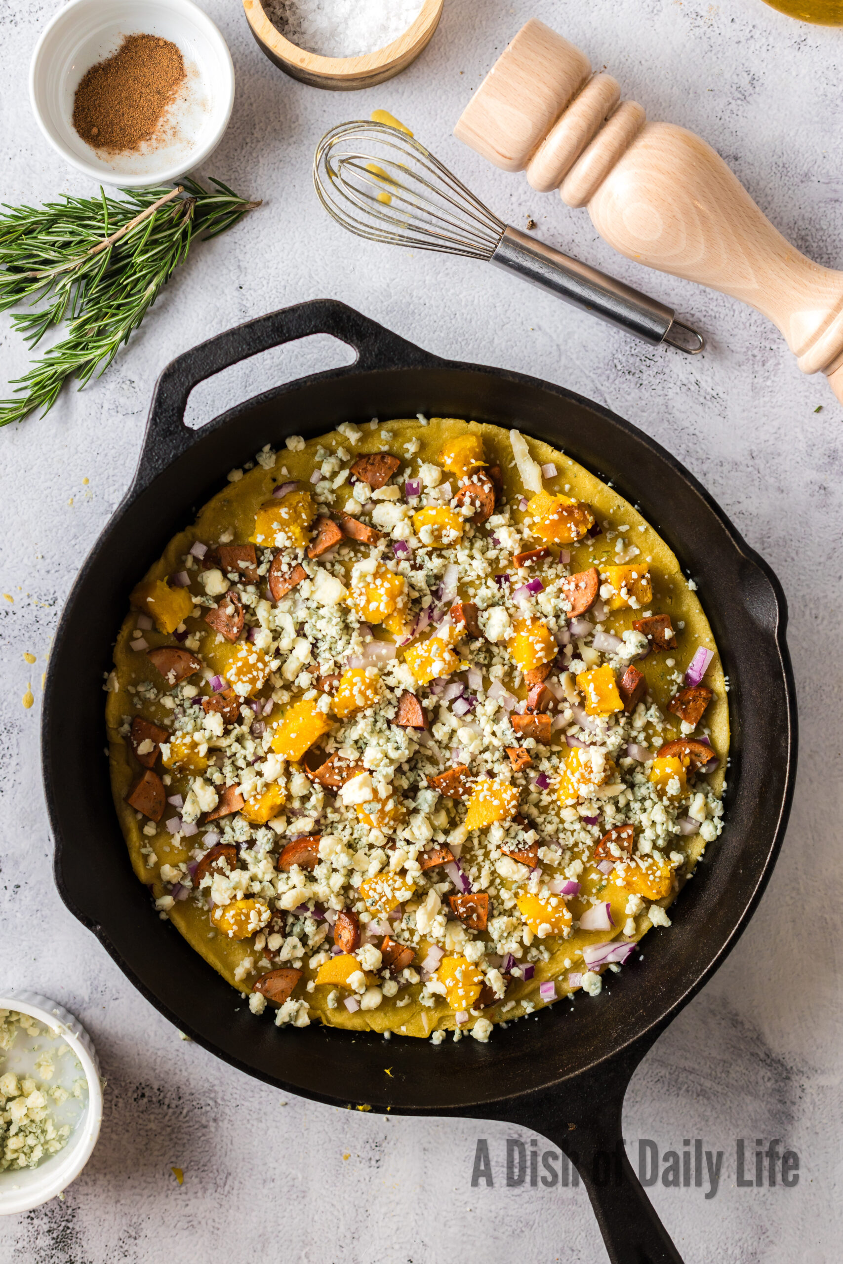 all ingredients for acorn squash pizza on crust in cast iron.