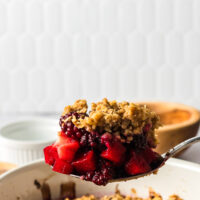 wooden spoon scooping out a portion of blackberry apple crumble