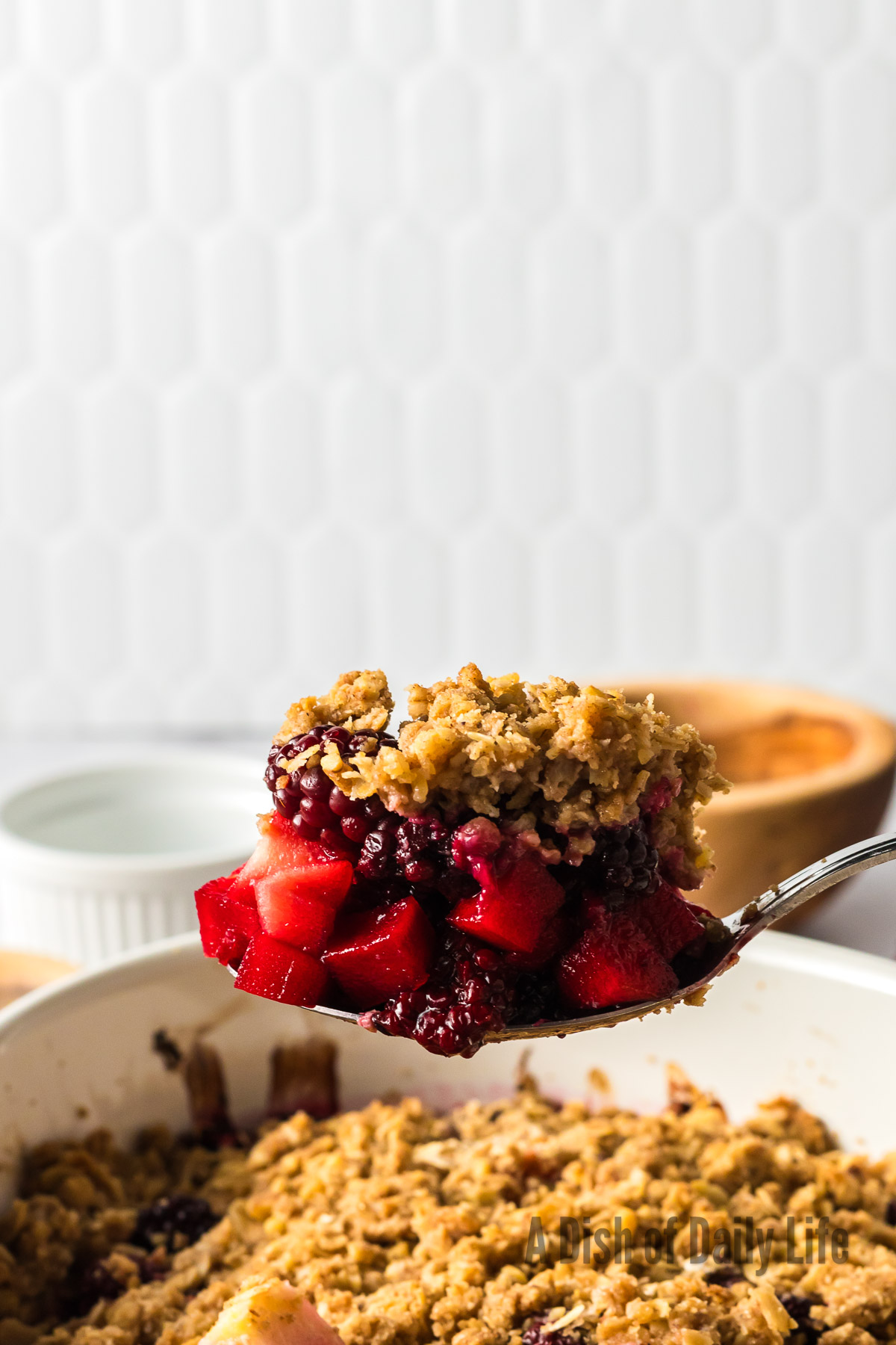 wooden spoon scooping out a portion of blackberry apple crumble