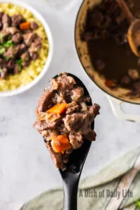 spoon scooping a portion of bone broth out of bowl