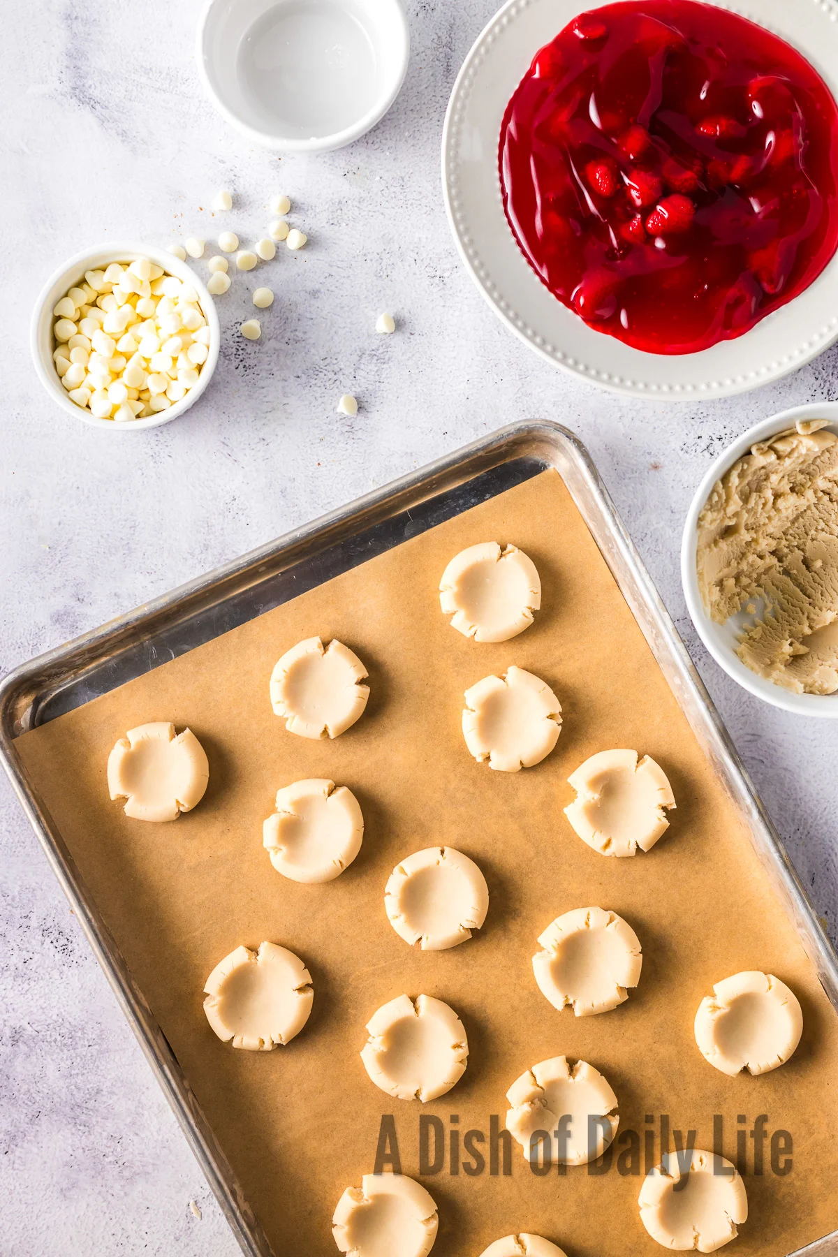cookie dough on cookie sheet with a dent in each dough ball.