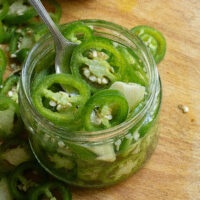 spoon scooping out ready to eat pickled jalapenos.
