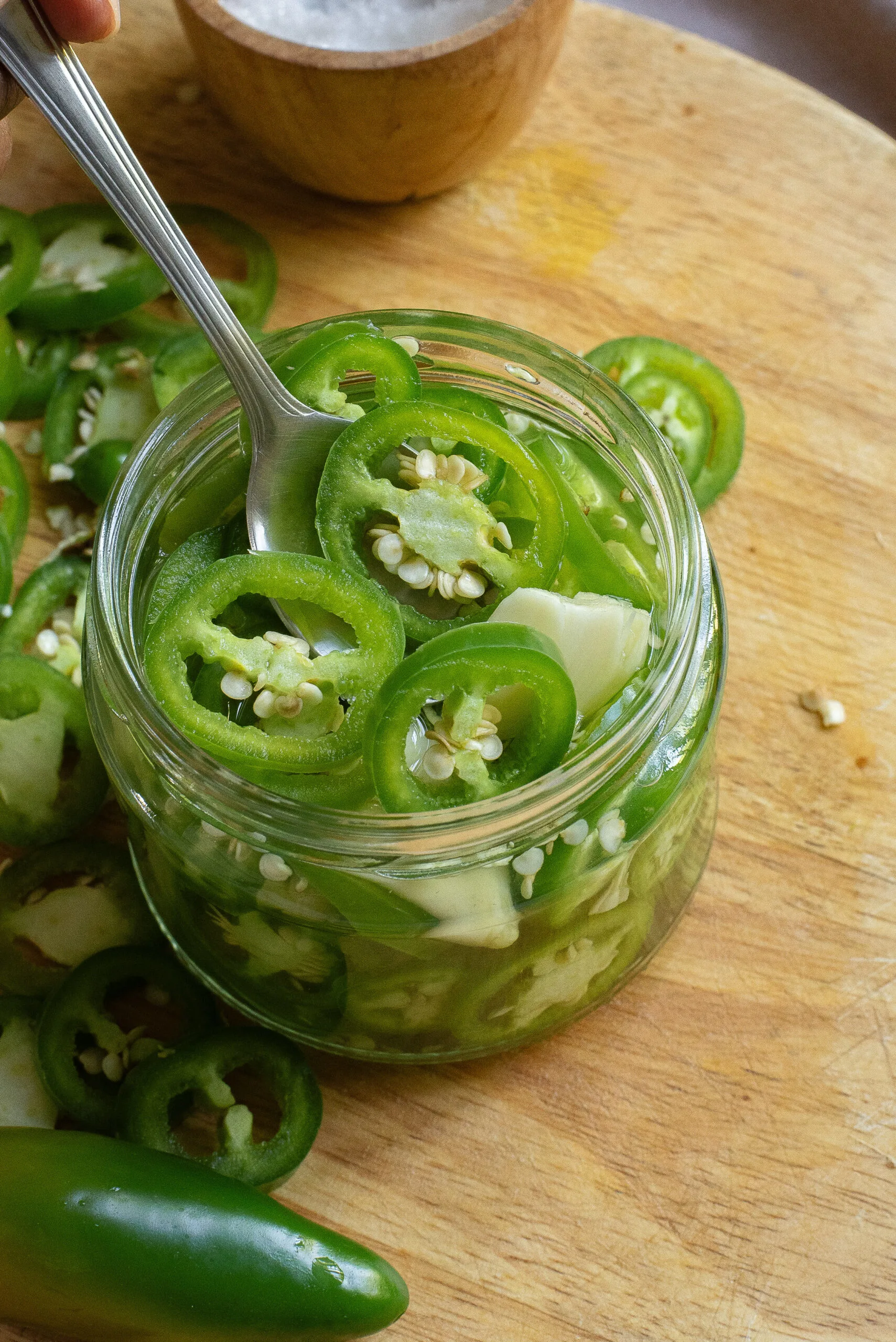 spoon scooping out ready to eat pickled jalapenos.
