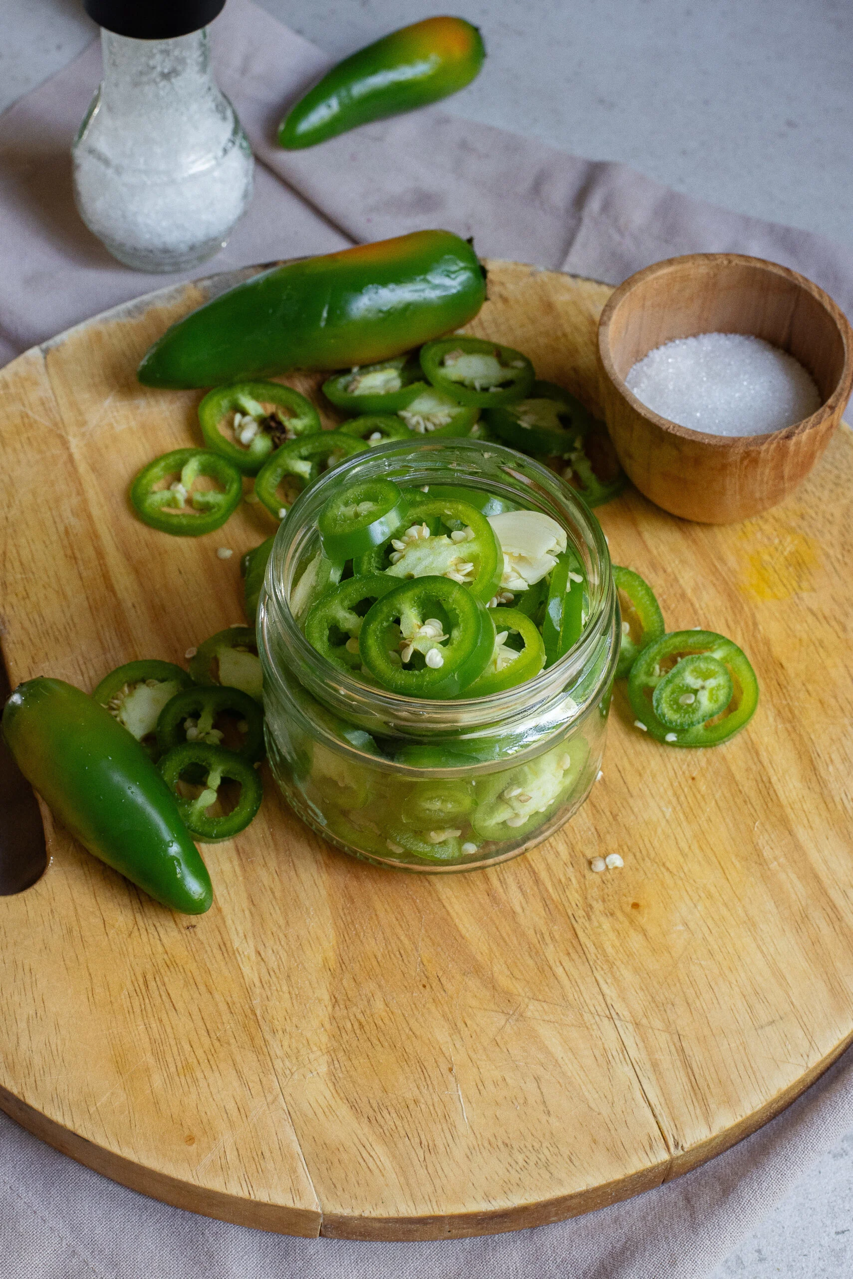 zoomed out image of jalapenos and garlic in a jar with vinegar added