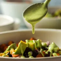 spoon drizzling dressing over sweet potato salad