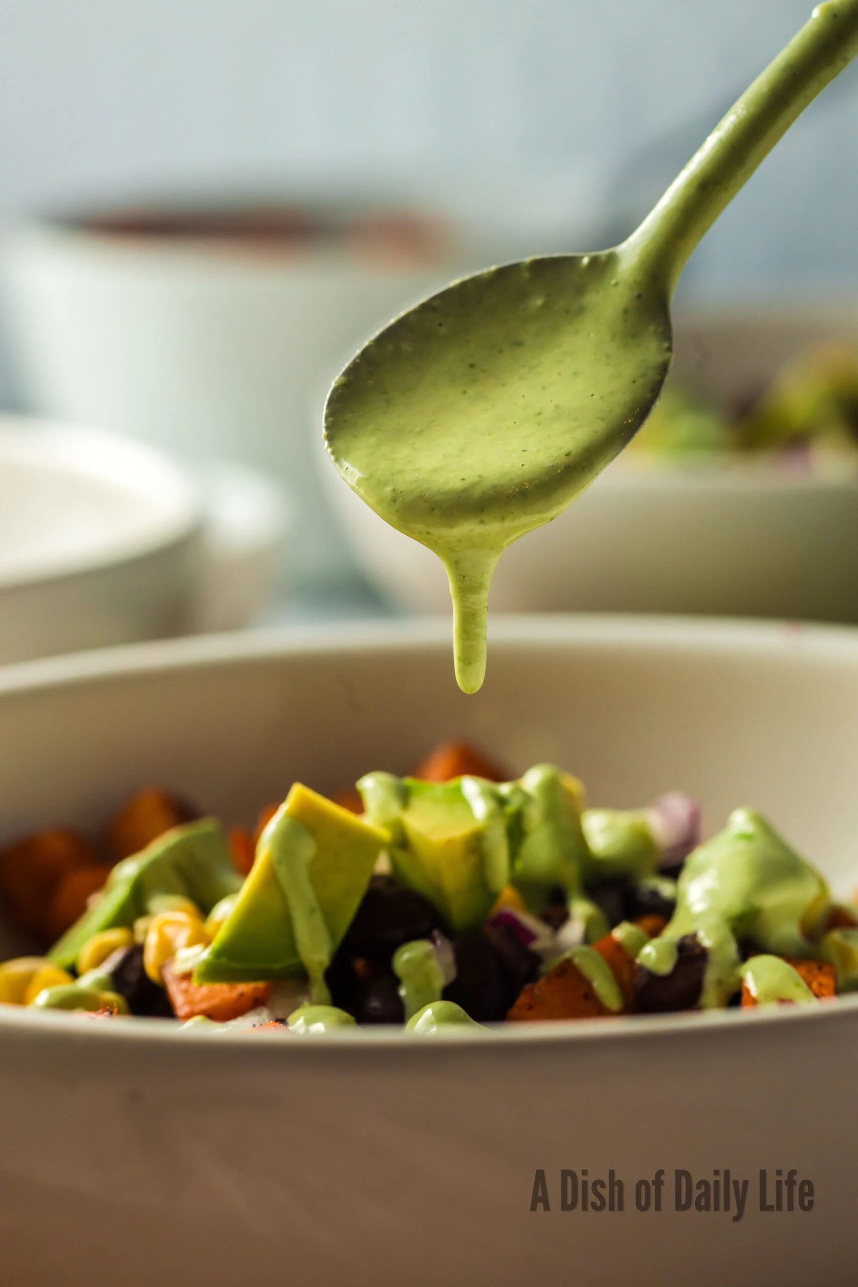 spoon drizzling dressing over sweet potato salad